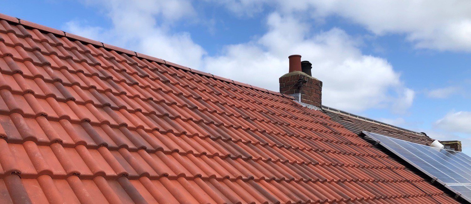 Completed red pantile roof with chimney stack