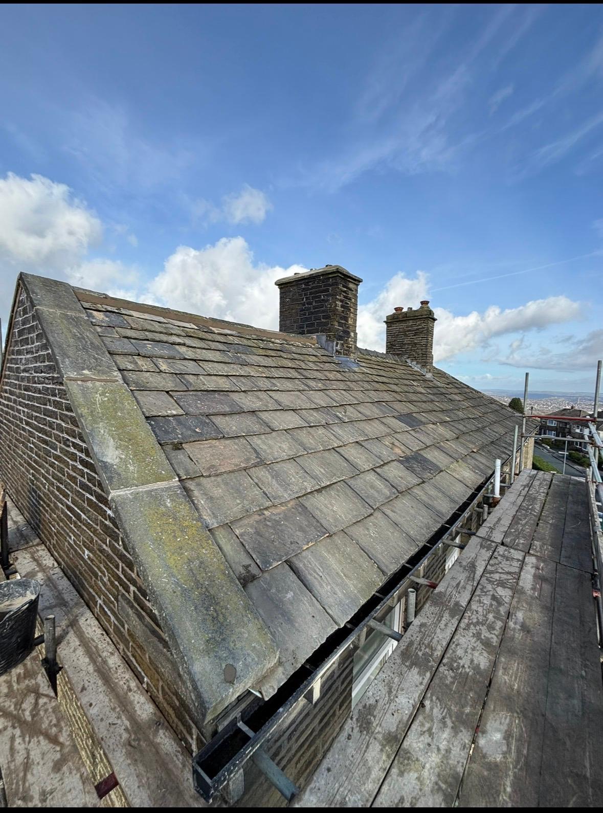 Stone slate roof with new lead verge detail and chimney stacks, viewed from scaffold